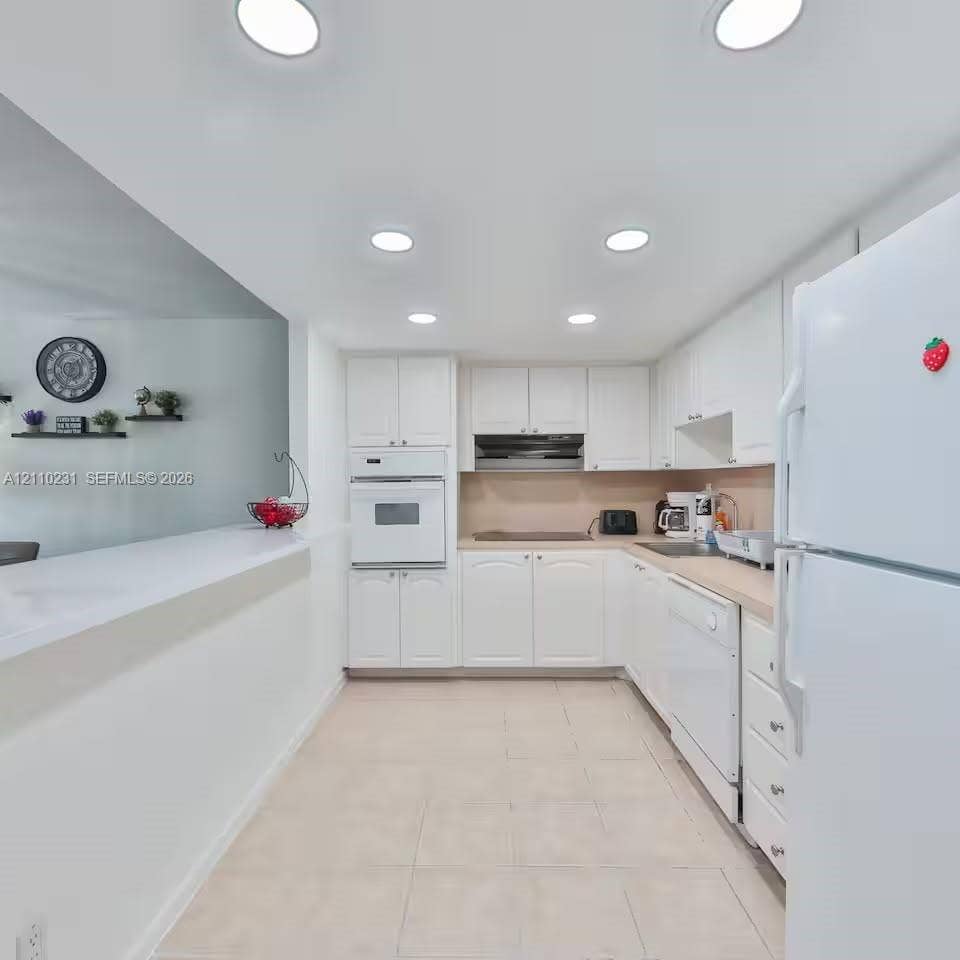 19370 Collins Avenue, #622, Sunny Isles Beach, FL 33160 Kitchen featuring white cabinetry, recessed lighting, tile flooring, integrated wall oven, and a peninsula counter