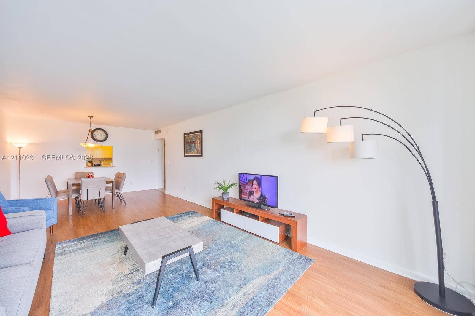 19370 Collins Avenue, #622, Sunny Isles Beach, FL 33160 Open-concept interior featuring wood-finish flooring, smooth ceilings, and a kitchen pass-through window with a hanging pendant light fixture