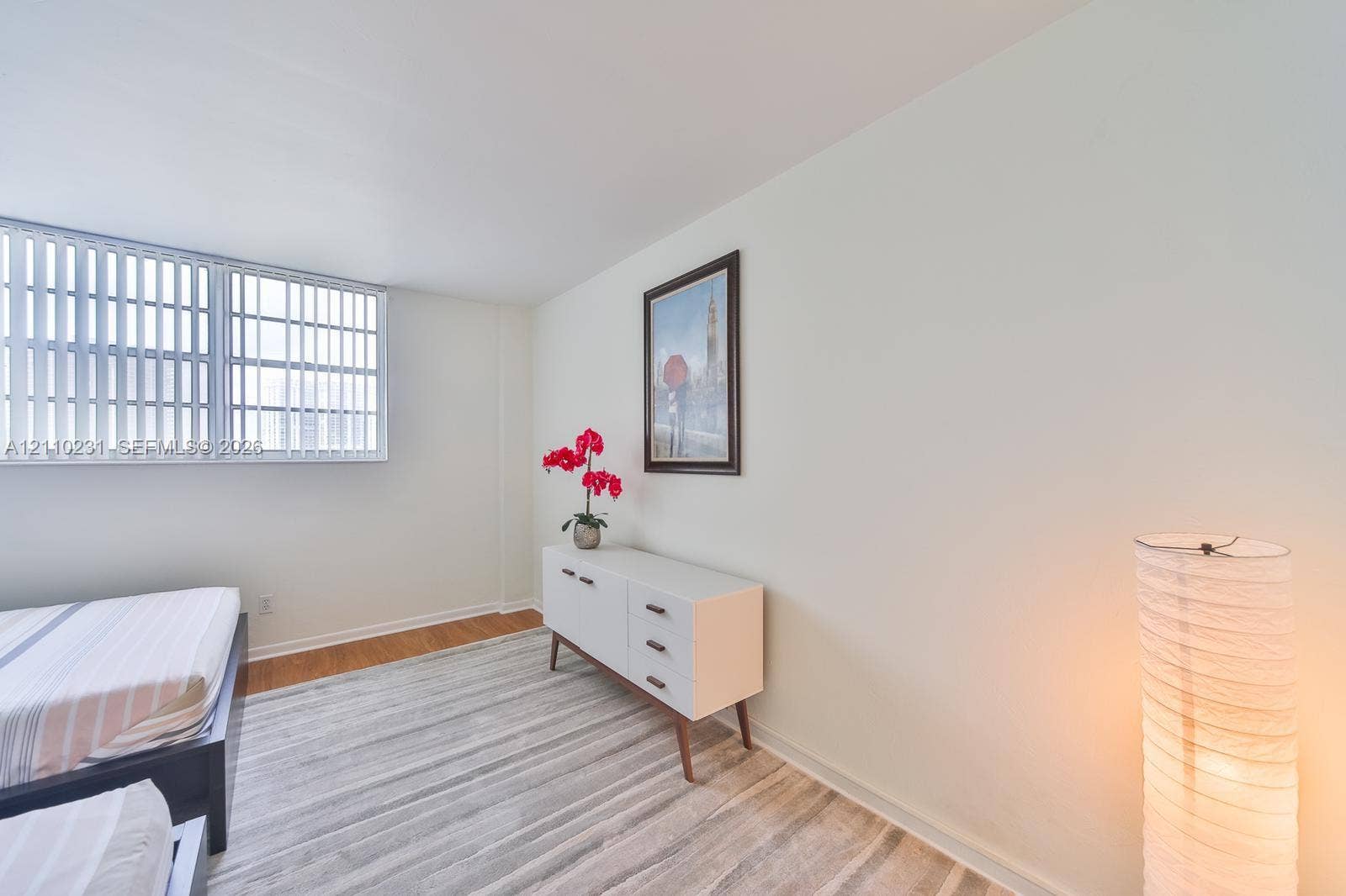 19370 Collins Avenue, #622, Sunny Isles Beach, FL 33160 Neutral-toned room featuring expansive horizontal windows with vertical blinds and wood-finish flooring