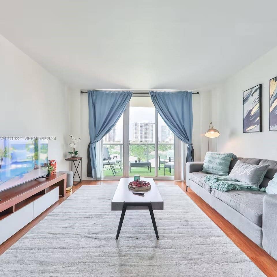 19370 Collins Avenue, #622, Sunny Isles Beach, FL 33160 Living area featuring wood-finish flooring, floor-to-ceiling glass sliding doors, and a private balcony