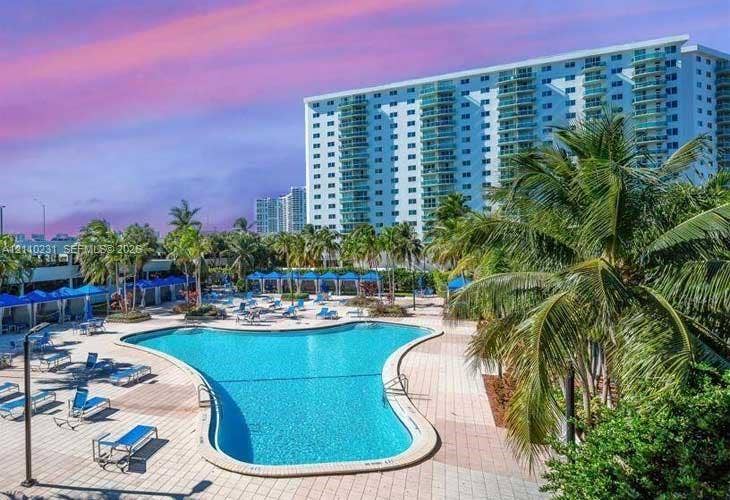 19370 Collins Avenue, #622, Sunny Isles Beach, FL 33160 Outdoor swimming pool surrounded by a paved deck, shaded cabanas, and mature palm trees