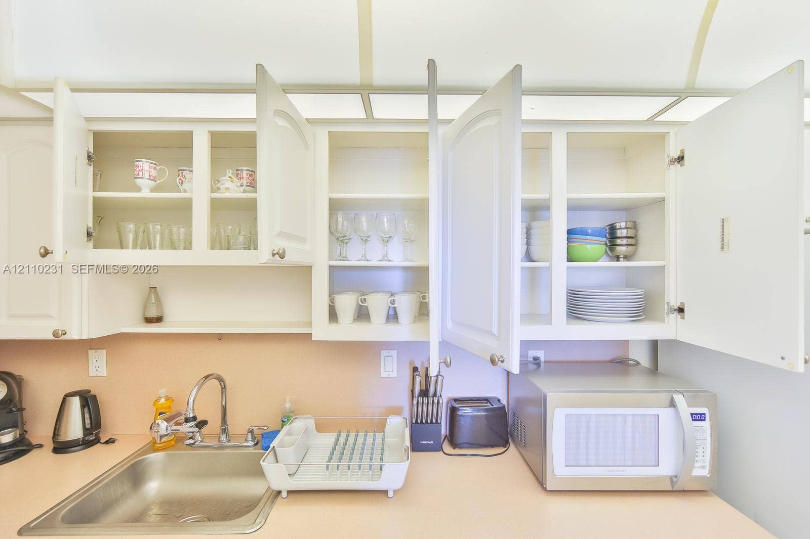 19370 Collins Avenue, #622, Sunny Isles Beach, FL 33160 White cabinetry with paneled doors, solid-surface countertop, stainless steel sink, and integrated overhead lighting