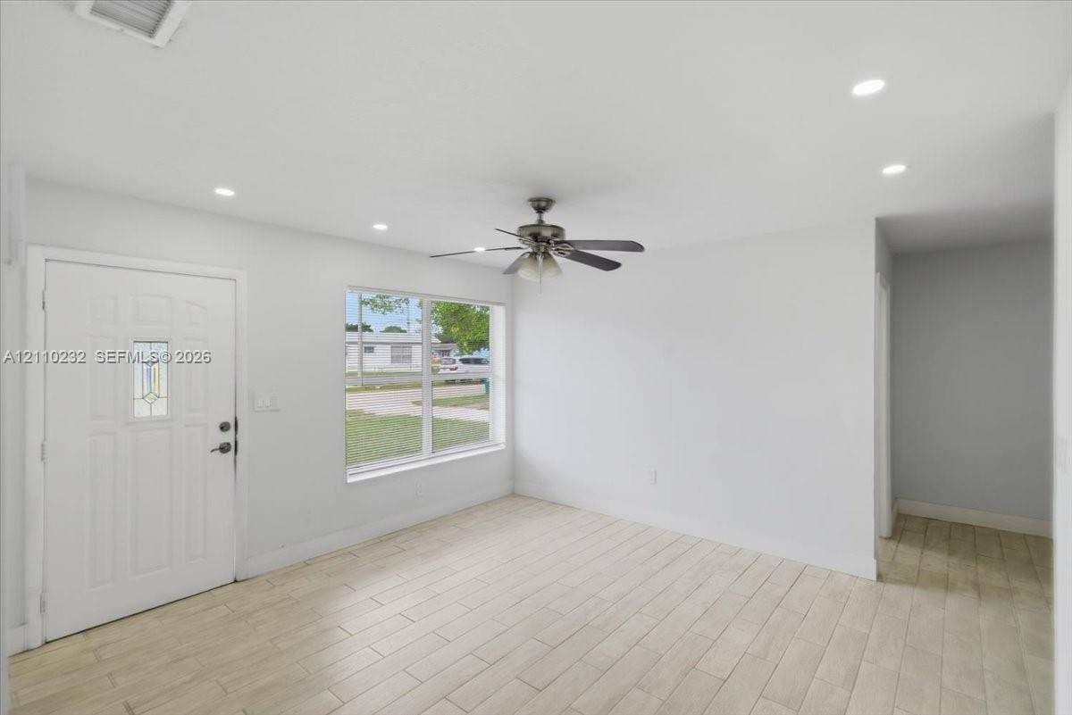 Interior space featuring wood-finish tile flooring, recessed ceiling lighting, a multi-blade ceiling fan, and a six-panel entry door with an integrated glass light