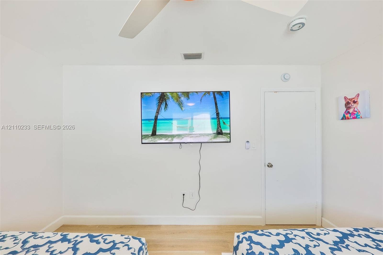 614 S Crescent Drive, Hollywood, FL 33021 Neutral-toned interior featuring light-finished flooring, a ceiling fan, and a wall-mounted flat-panel television
