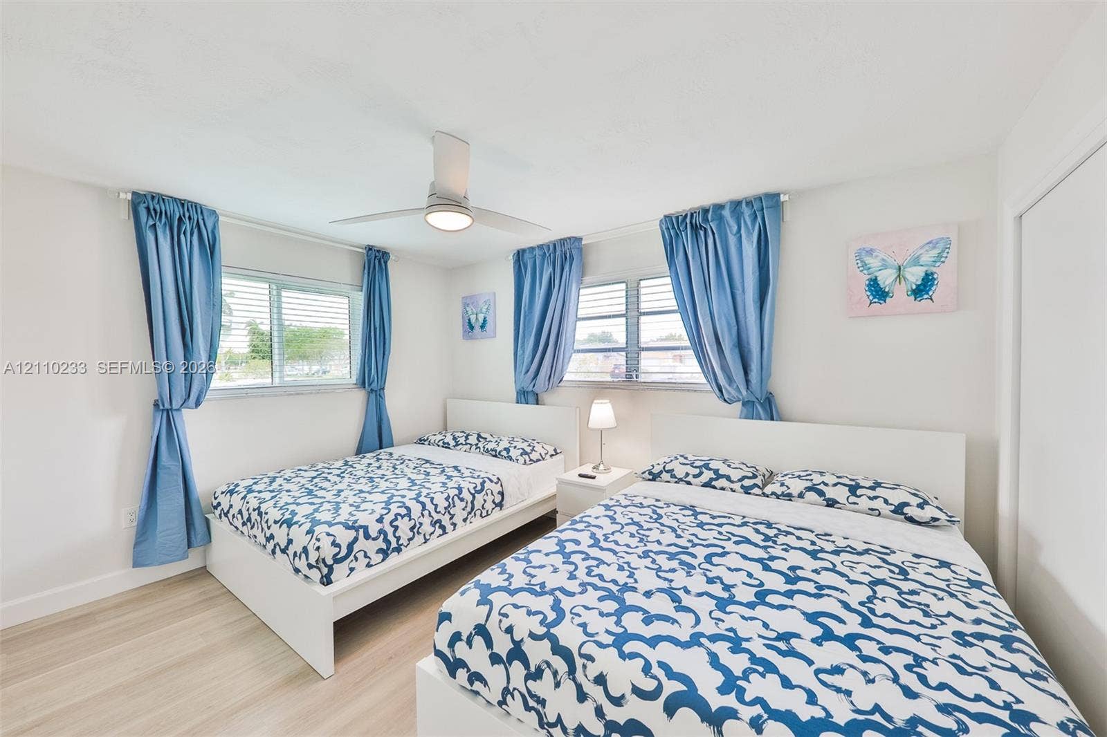 614 S Crescent Drive, Hollywood, FL 33021 Bedroom featuring wood-finish flooring, dual horizontal sliding windows, and a central ceiling fan with integrated lighting