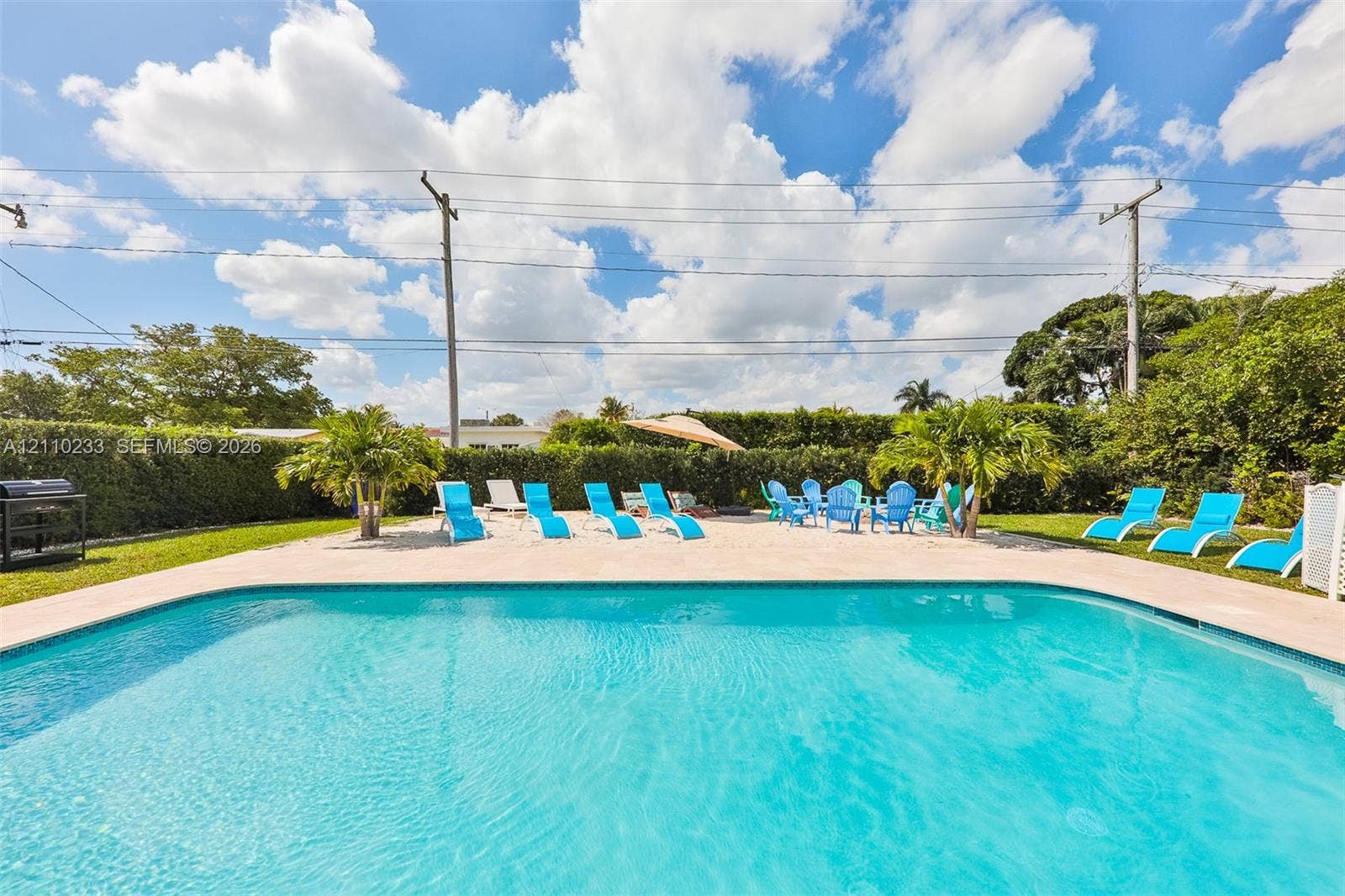 614 S Crescent Drive, Hollywood, FL 33021 In-ground swimming pool with light-colored coping, concrete patio, and dense perimeter hedge landscaping