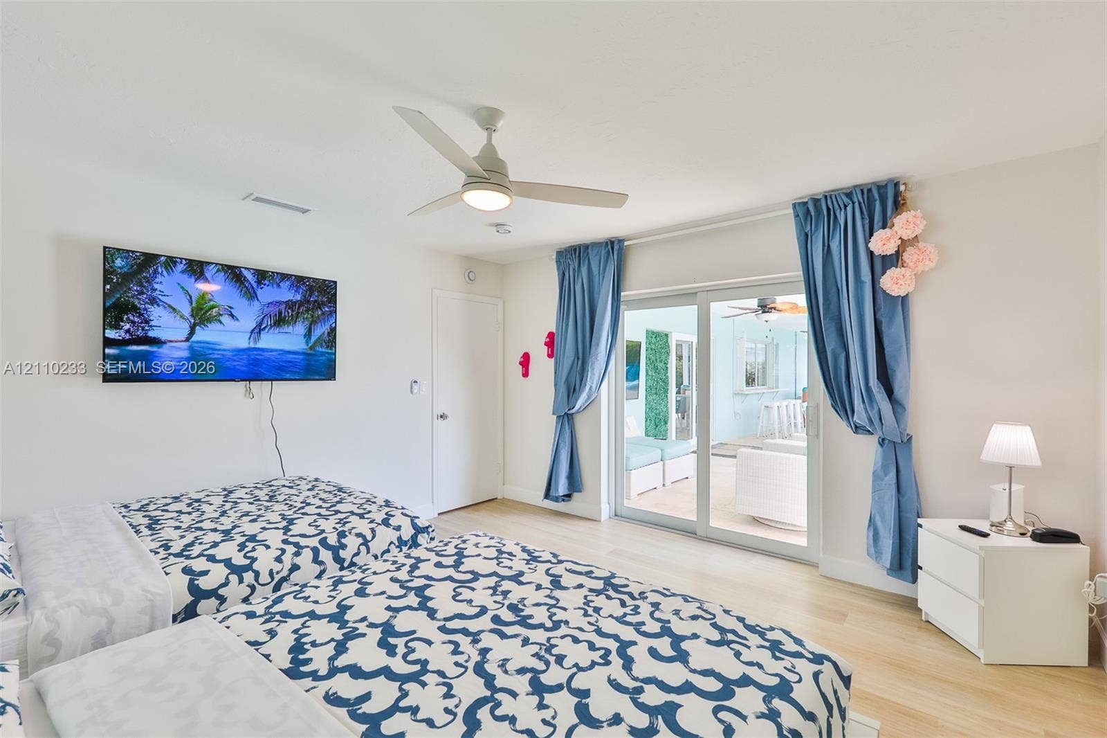 614 S Crescent Drive, Hollywood, FL 33021 Light-toned wood-finish flooring, ceiling fan with integrated lighting, and glass sliding doors
