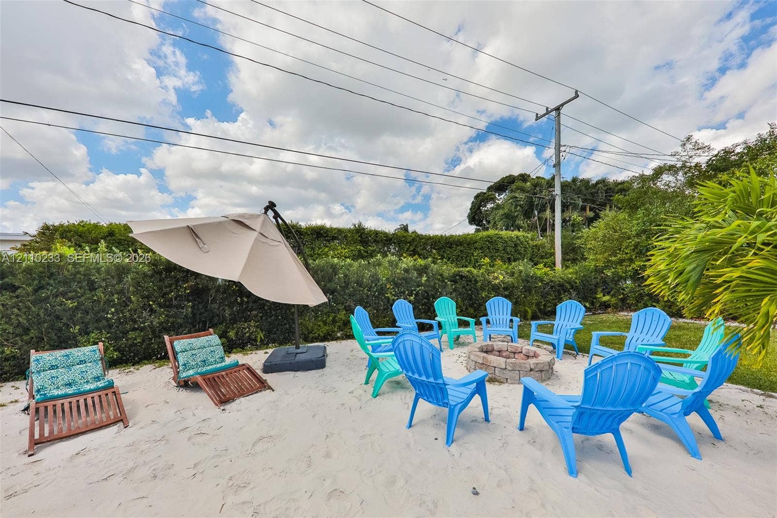 614 S Crescent Drive, Hollywood, FL 33021 Outdoor space featuring a sand-covered ground, a stone-block fire pit, and mature perimeter landscaping