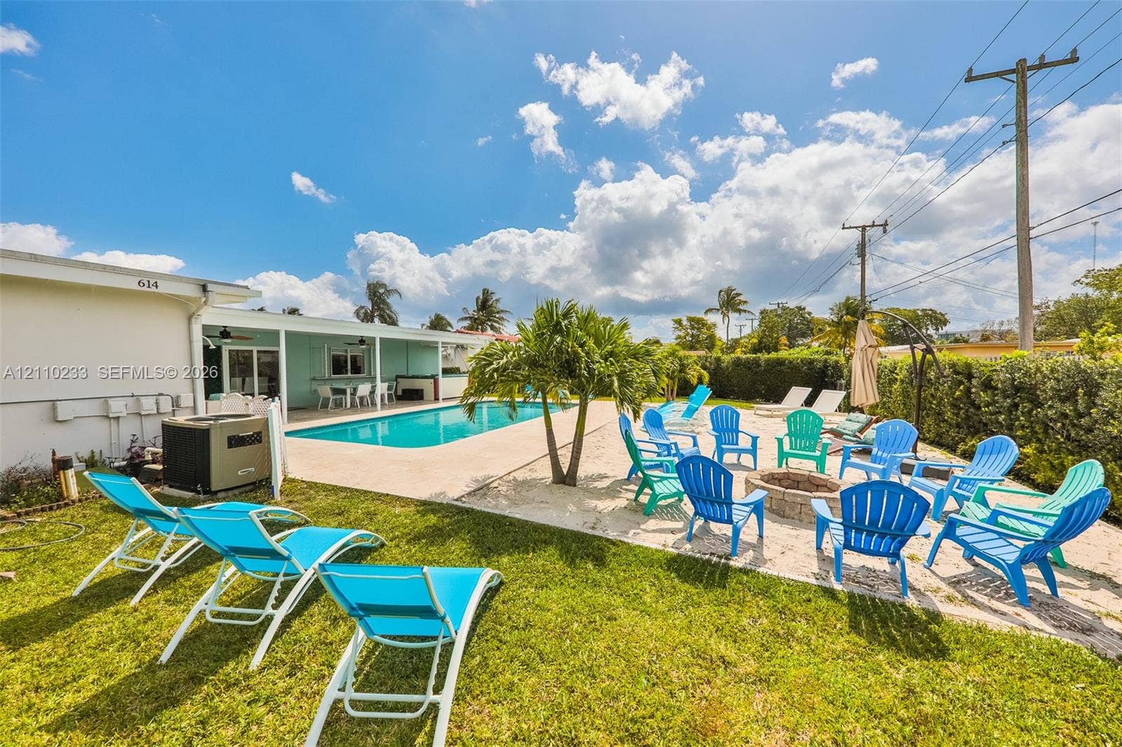 614 S Crescent Drive, Hollywood, FL 33021 Outdoor living space featuring an inground swimming pool, concrete patio, circular stone fire pit, and lawn area