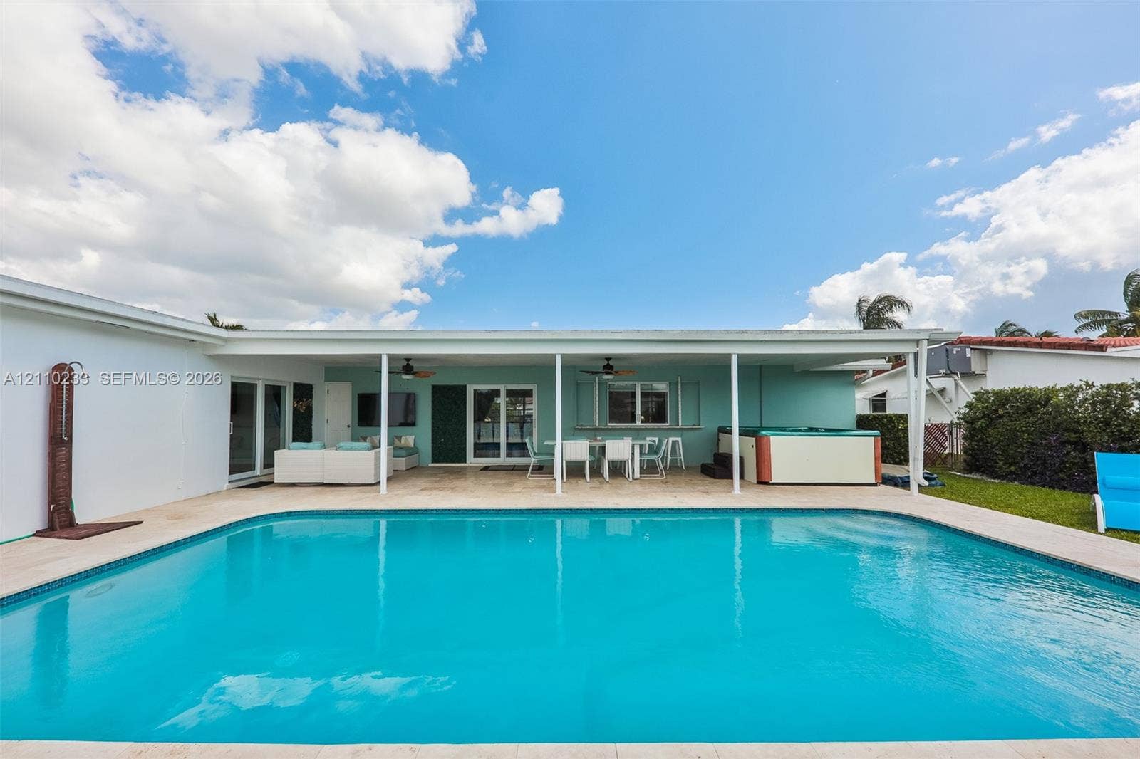 614 S Crescent Drive, Hollywood, FL 33021 Swimming pool with stone paver decking, covered patio with dual ceiling fans, exterior wall-mounted shower fixture, and built-in hot tub