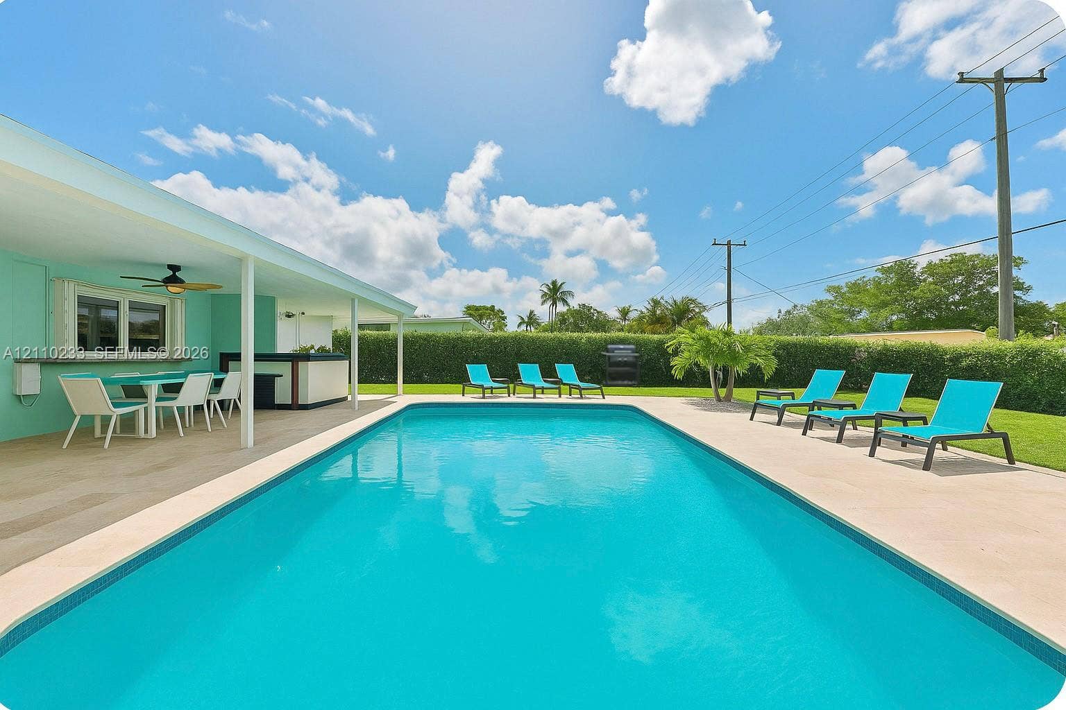 614 S Crescent Drive, Hollywood, FL 33021 In-ground swimming pool with a surrounding paved deck, covered patio, and manicured hedge perimeter