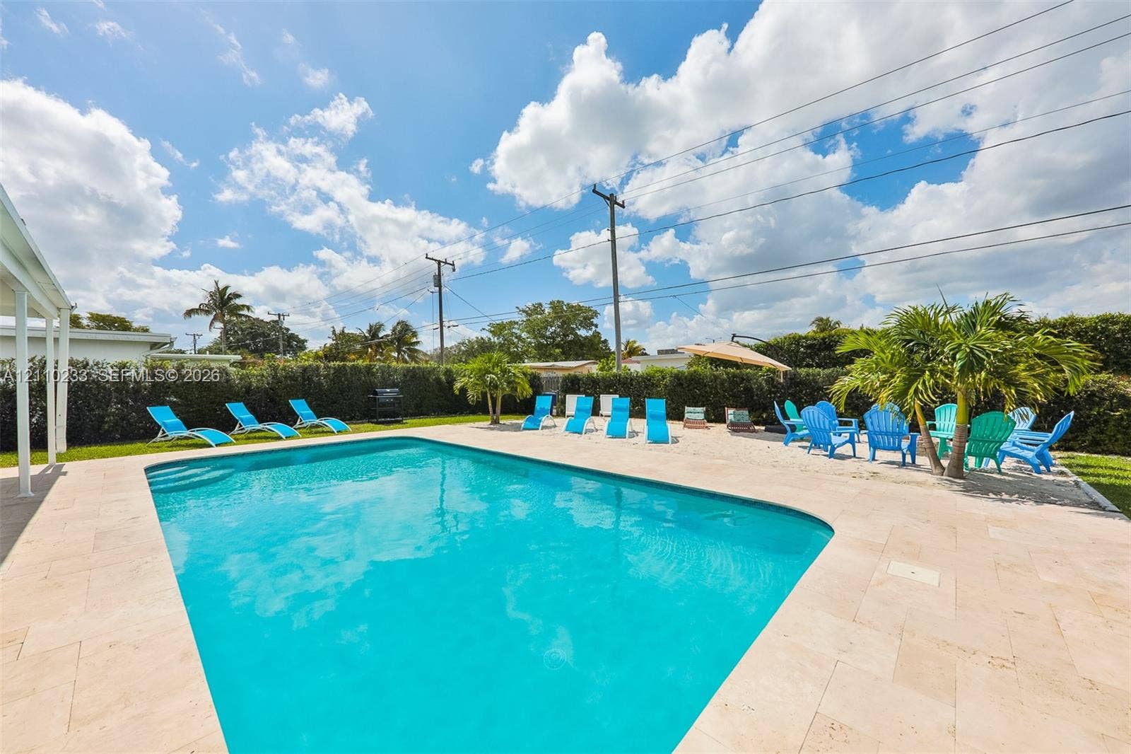 614 S Crescent Drive, Hollywood, FL 33021 In-ground swimming pool with stone-finish decking, bordered by a privacy hedge and landscaping