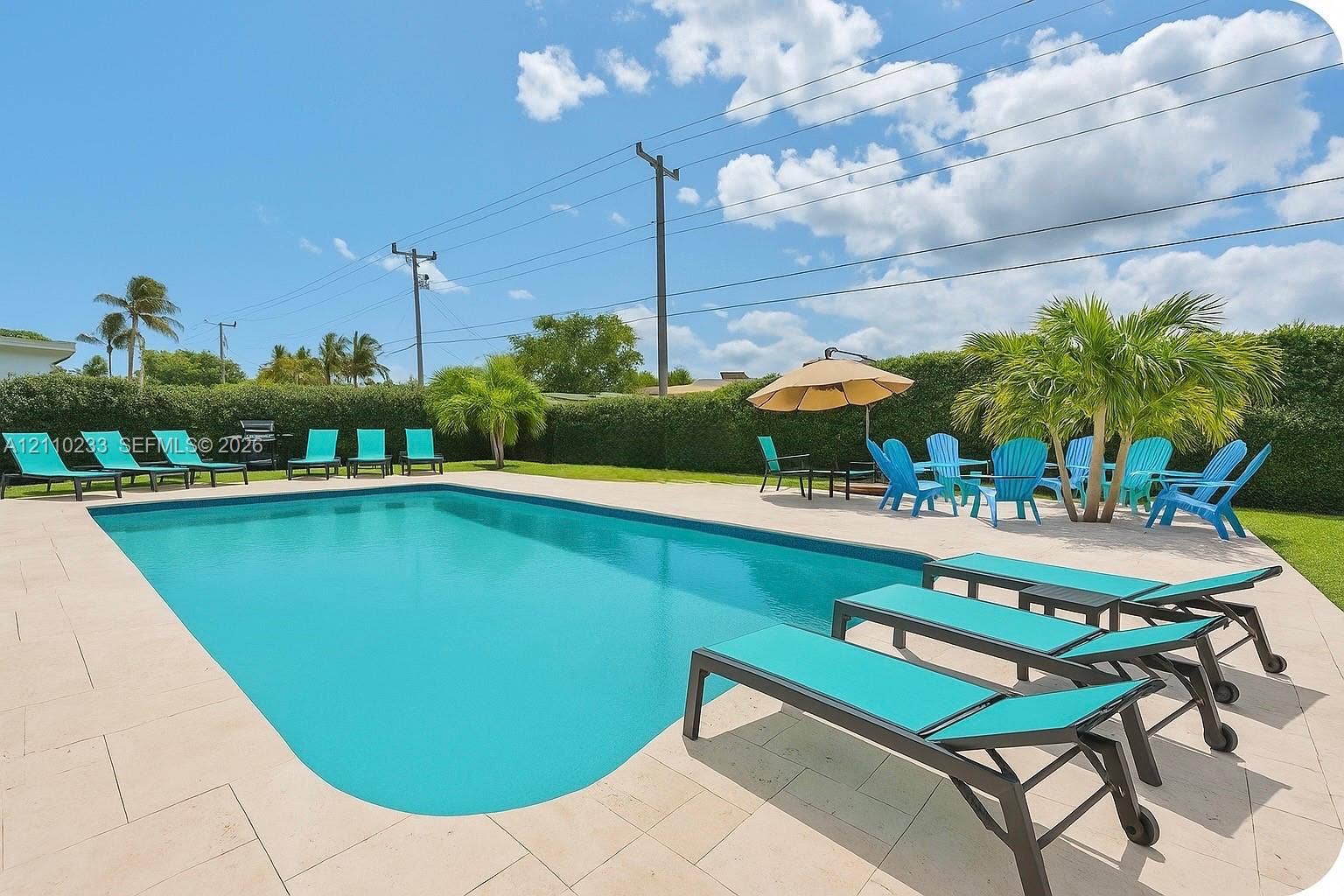 614 S Crescent Drive, Hollywood, FL 33021 In-ground swimming pool featuring a light-toned stone paver deck and perimeter privacy hedging