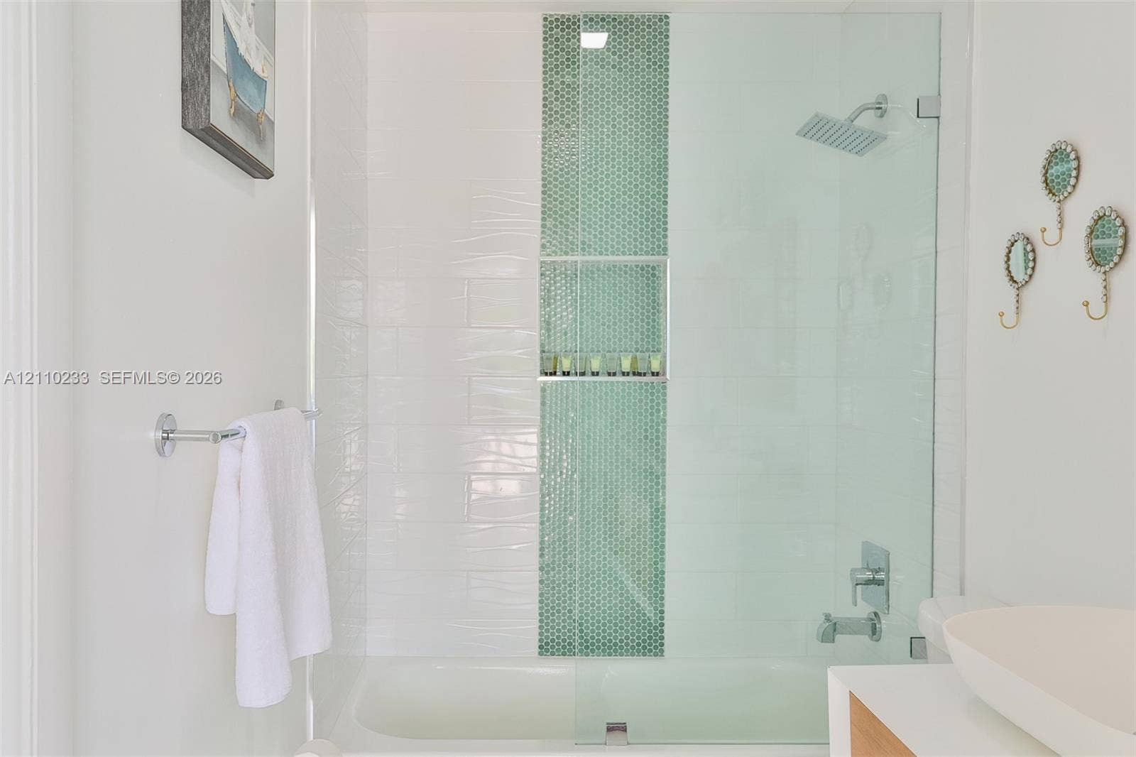 614 S Crescent Drive, Hollywood, FL 33021 Shower and tub combination featuring white wall tiling, a vertical mosaic accent stripe, built-in recessed shelving, a glass shower panel, and a rectangular rainfall showerhead