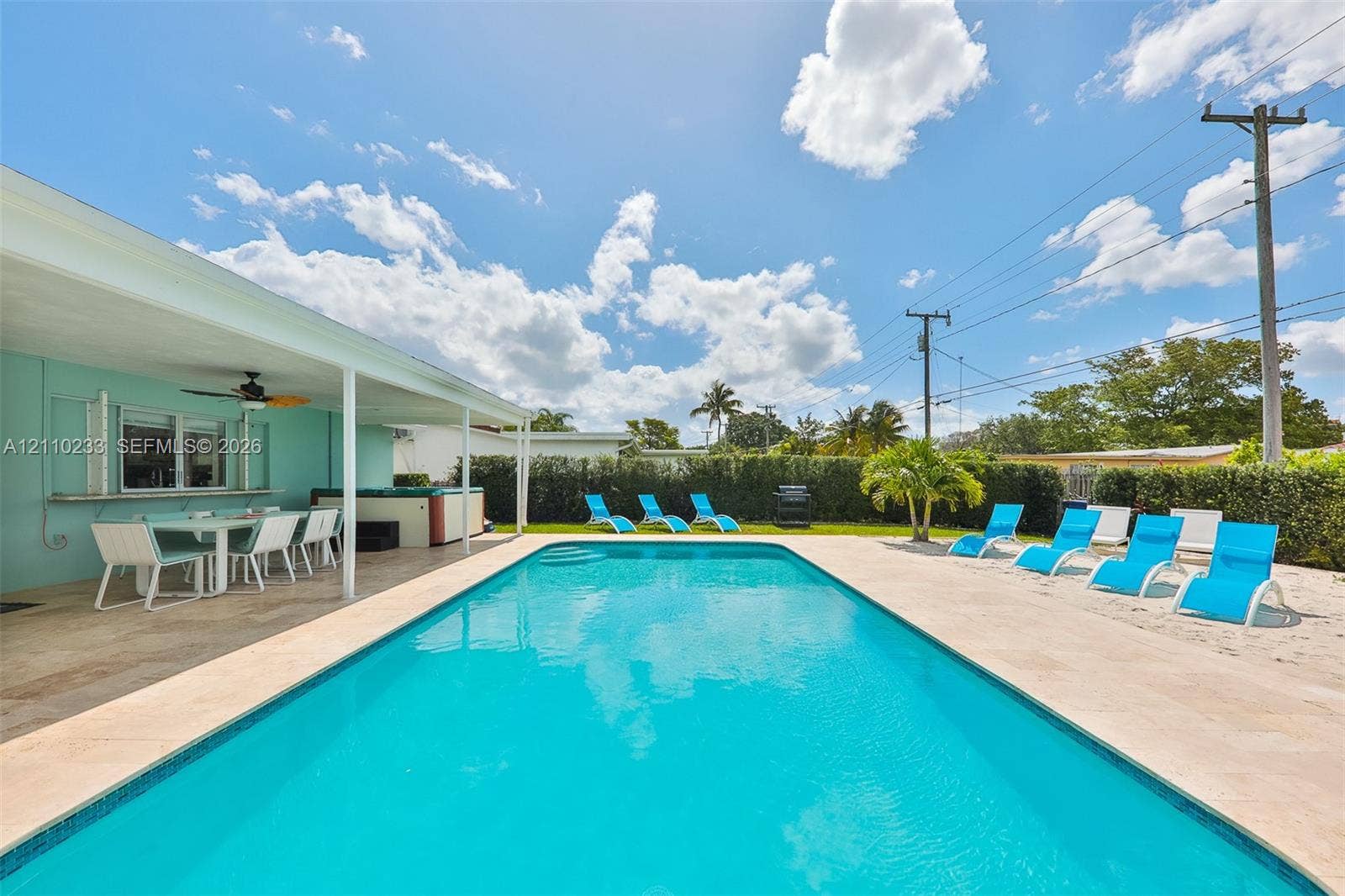 614 S Crescent Drive, Hollywood, FL 33021 In-ground swimming pool featuring a concrete paver deck, covered outdoor patio, and perimeter hedge landscaping