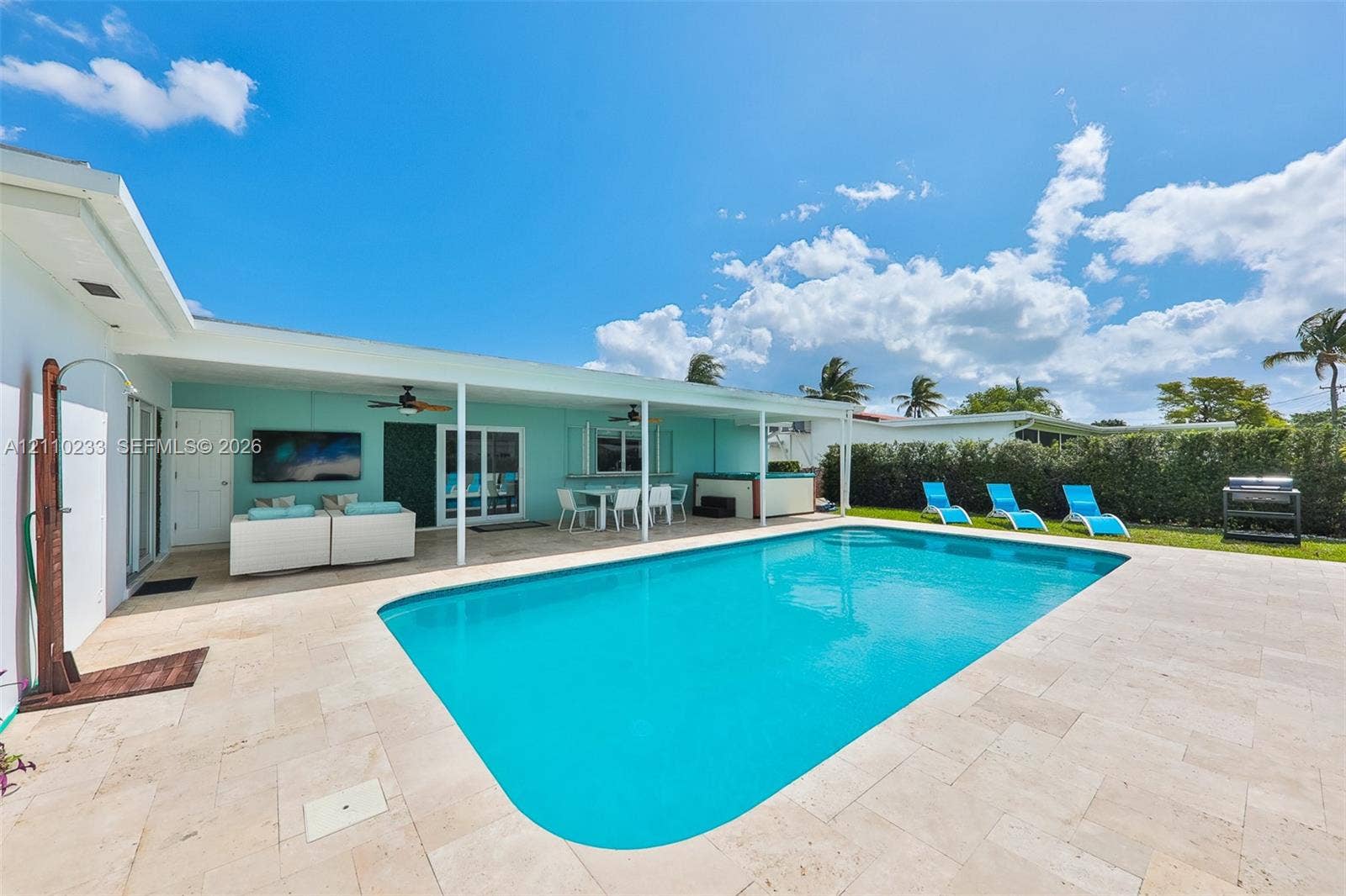 614 S Crescent Drive, Hollywood, FL 33021 In-ground swimming pool with stone-tiled patio, covered lanai, outdoor shower, and perimeter hedging