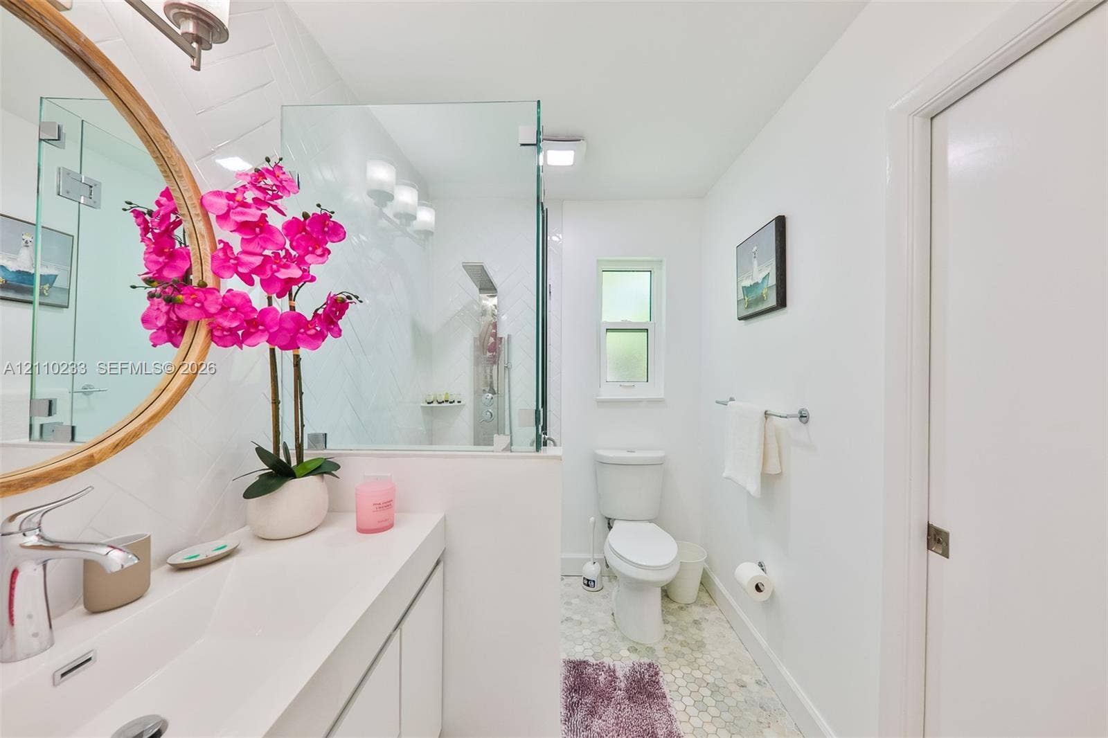 614 S Crescent Drive, Hollywood, FL 33021 Bathroom featuring a vanity with an integrated basin, a walk-in shower with a glass enclosure and herringbone tile surround, a polished metal rainfall showerhead, and hexagonal floor tiling