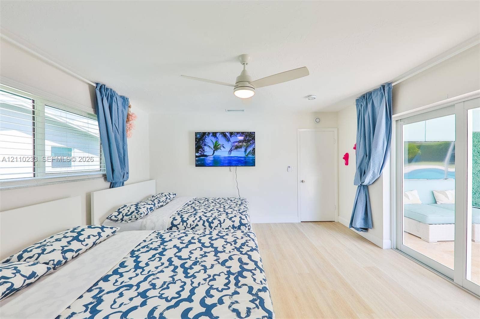 614 S Crescent Drive, Hollywood, FL 33021 Light-toned wood-finish flooring, ceiling fan with integrated lighting, and glass sliding doors providing exterior exposure