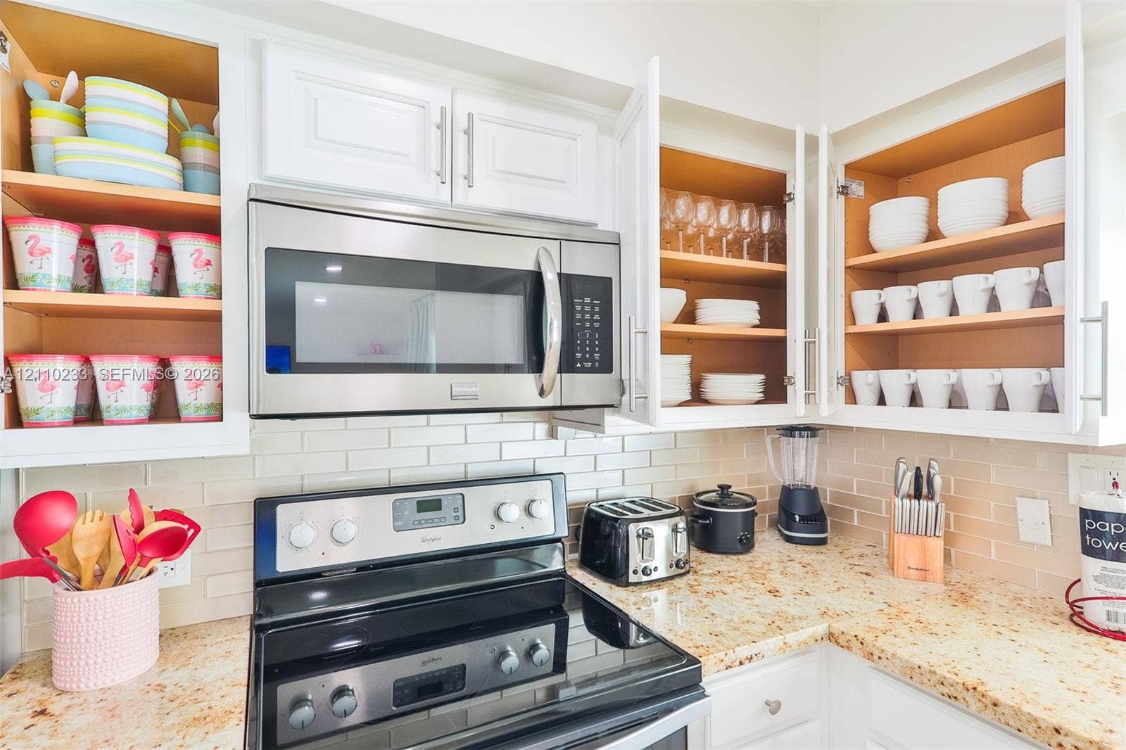 614 S Crescent Drive, Hollywood, FL 33021 Kitchen featuring white shaker-style cabinetry, stone countertops, stainless steel microwave, stainless steel range, and a subway tile backsplash