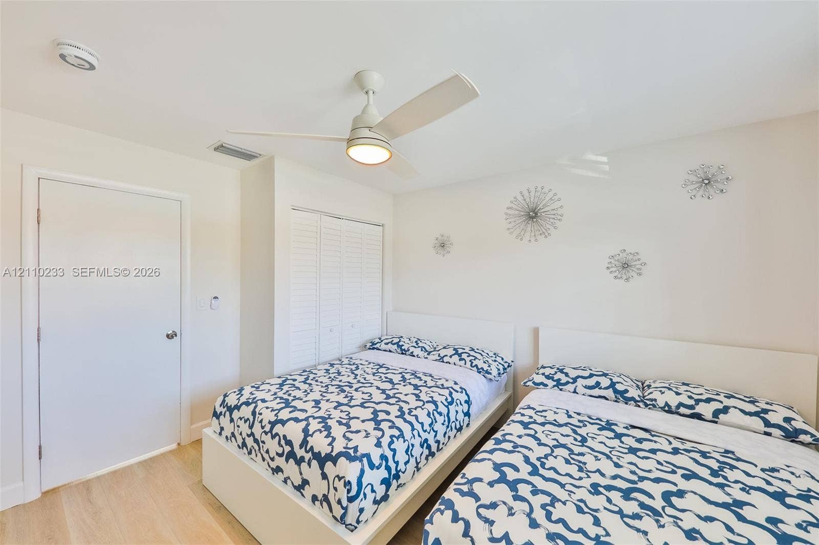 614 S Crescent Drive, Hollywood, FL 33021 Interior space featuring light-tone wood-finish flooring, a white ceiling fan with integrated lighting, and a closet with white louvered bi-fold doors