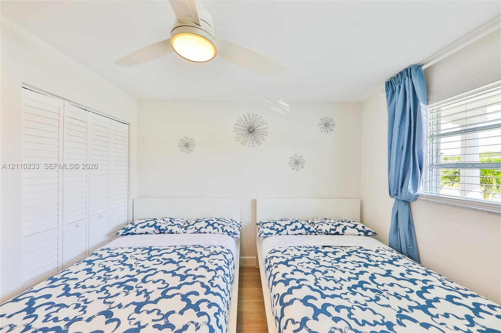 614 S Crescent Drive, Hollywood, FL 33021 White bifold closet doors, light wood-finish flooring, and a central ceiling fan with integrated lighting