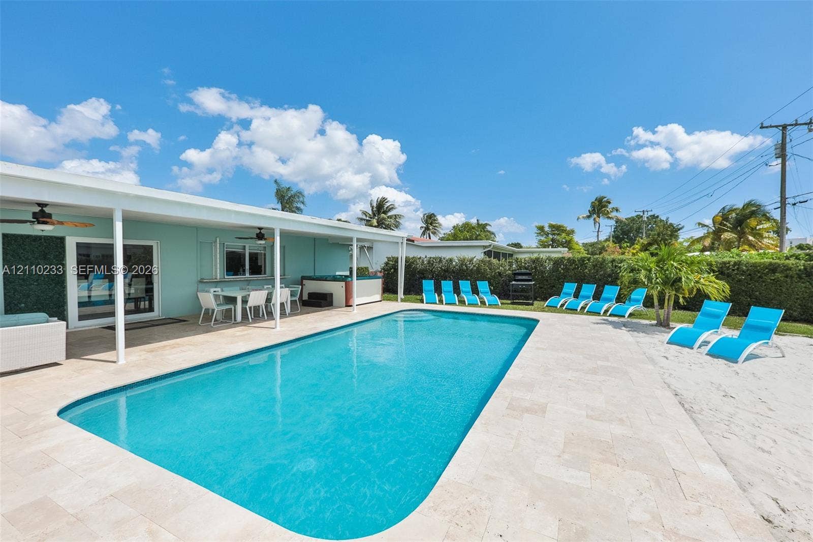 614 S Crescent Drive, Hollywood, FL 33021 Outdoor area featuring an in-ground swimming pool, expansive stone paver pool deck, covered patio, integrated hot tub, and privacy hedge