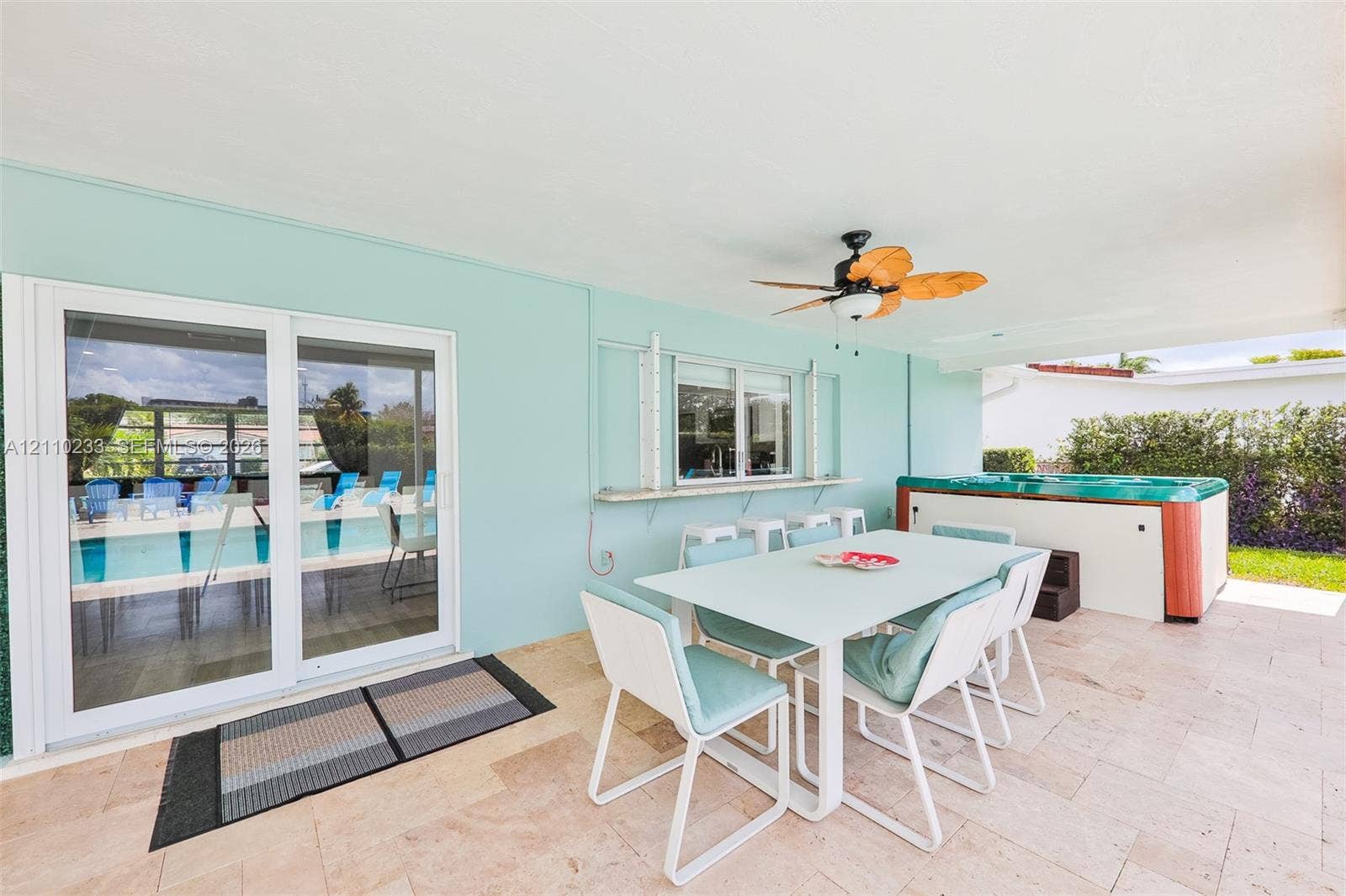 614 S Crescent Drive, Hollywood, FL 33021 Covered patio featuring stone tile flooring, an integrated serving ledge, a ceiling fan, and a built-in spa