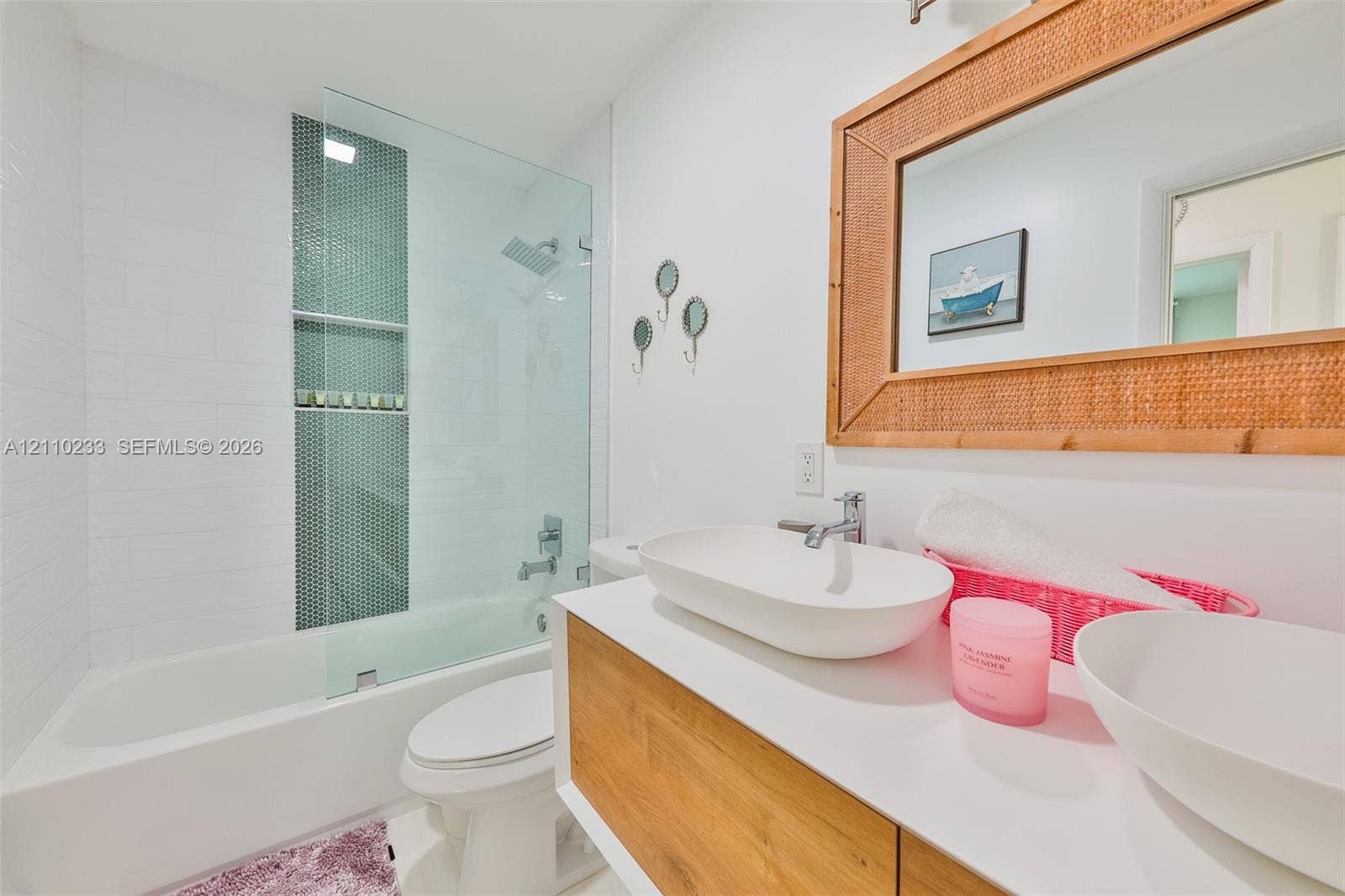 614 S Crescent Drive, Hollywood, FL 33021 Bathroom featuring a wood-finish floating vanity with dual vessel sinks, a glass-enclosed tub shower with mosaic tile inlay, and a built-in wall mirror