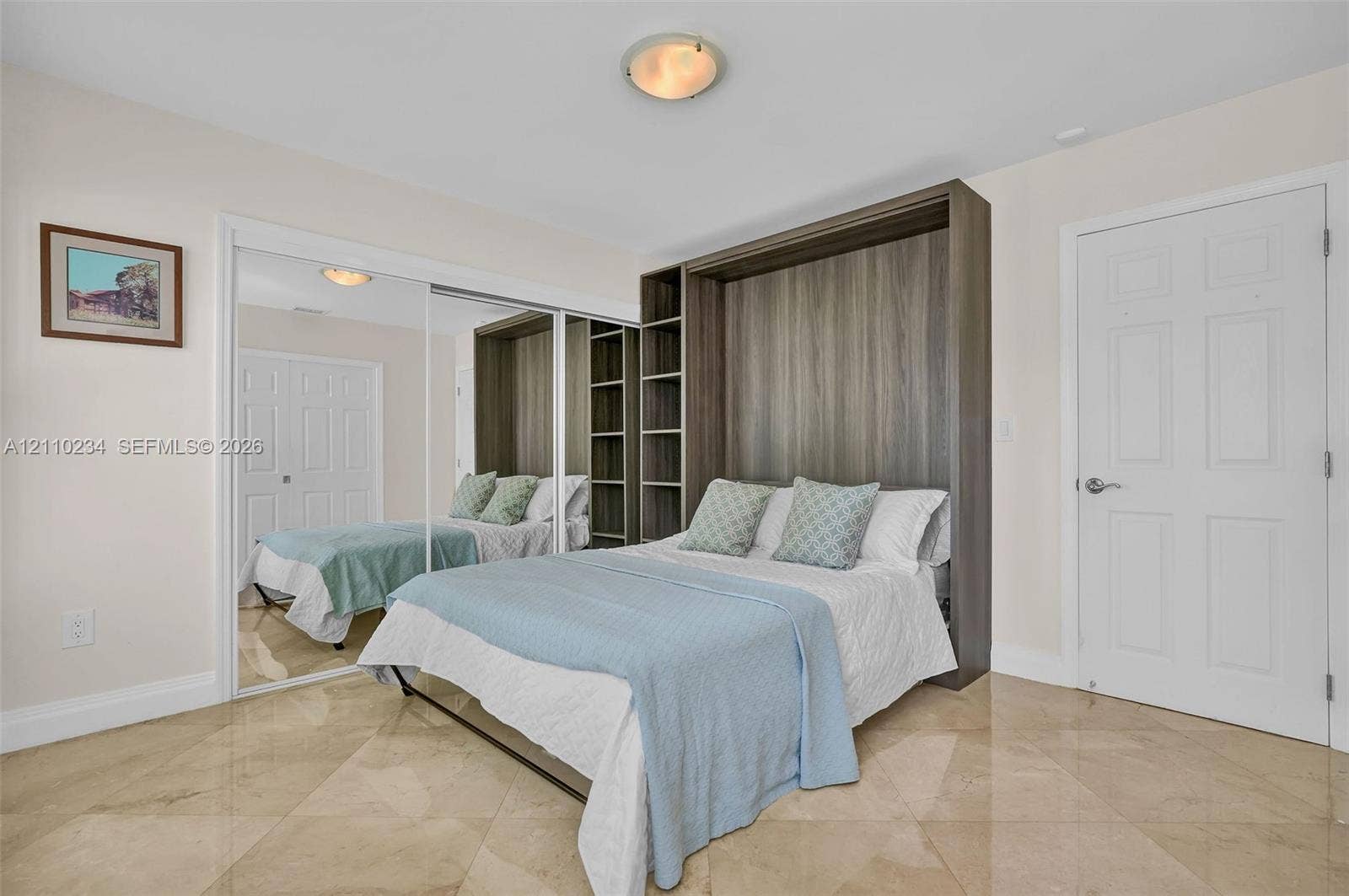 Built-in wood-finish wall bed unit with integrated shelving, polished stone tile flooring, and mirrored sliding closet doors