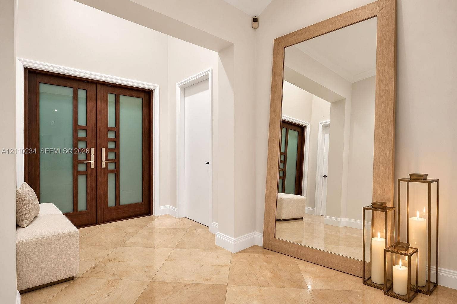 Double entry doors featuring frosted glass panels and metallic hardware, complemented by large-format stone tile flooring