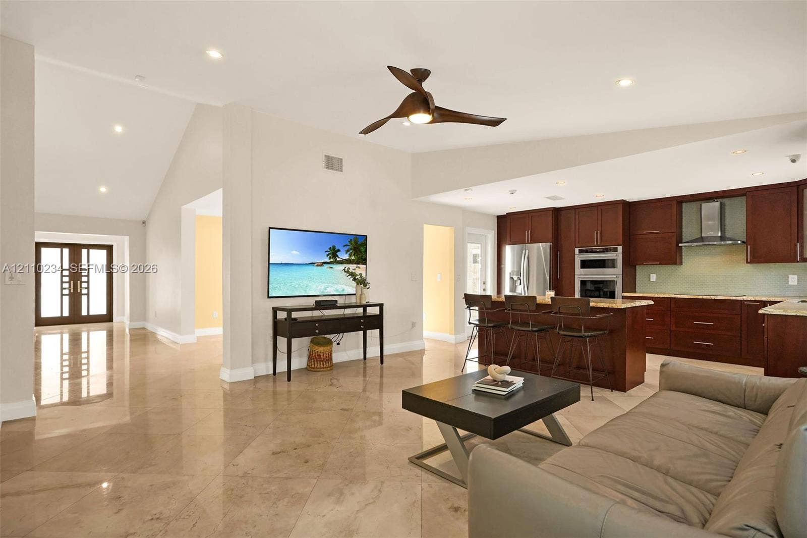 Open-concept living space featuring vaulted ceilings, polished stone tile flooring, recessed lighting, and a modern ceiling fan