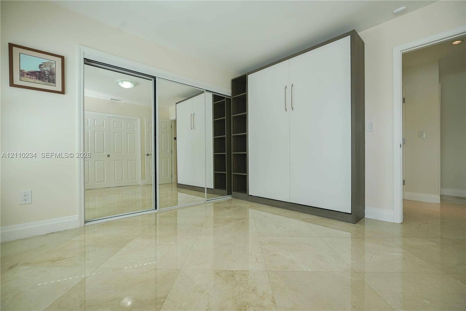 Polished stone flooring, floor-to-ceiling mirrored closet doors, and custom built-in cabinetry featuring integrated shelving and panel-front storage