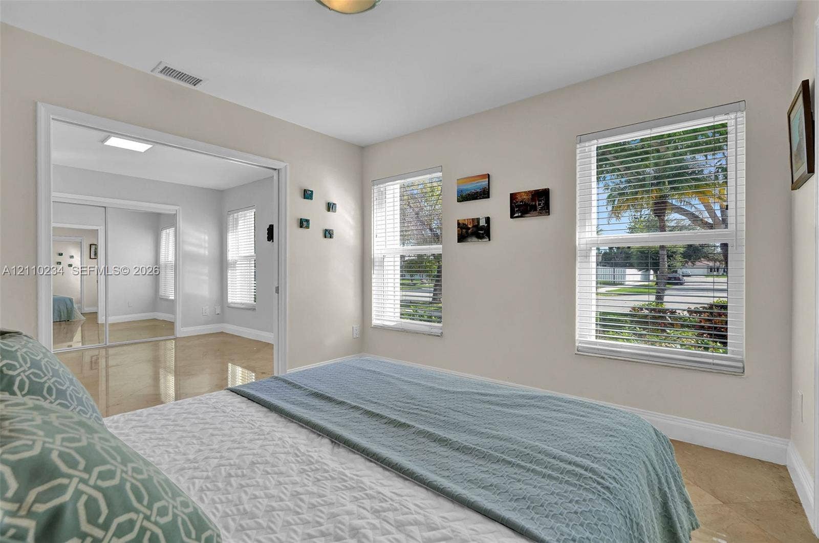 Neutral-toned interior featuring oversized tile flooring, large dual-pane windows with integrated blinds, and mirrored closet doors