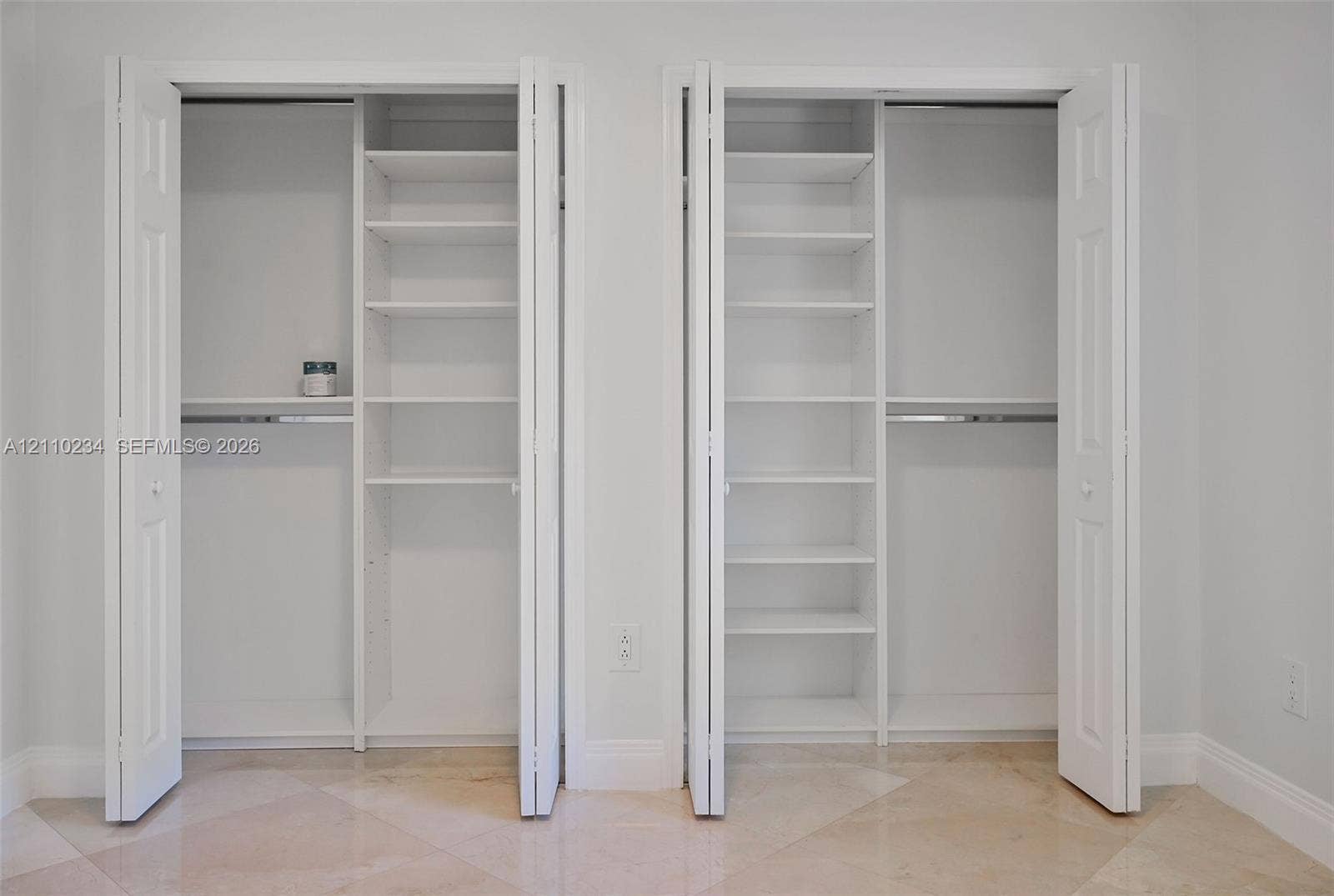 Dual closets featuring white bi-fold doors, built-in shelving units, and integrated clothing rods