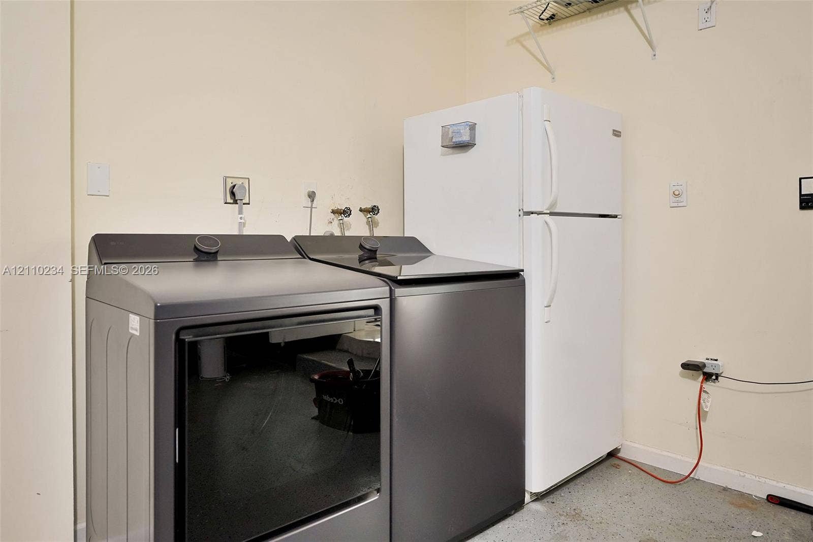 Laundry area featuring built-in shelving, plumbing connections for a washer and dryer, and a designated space for an upright refrigerator