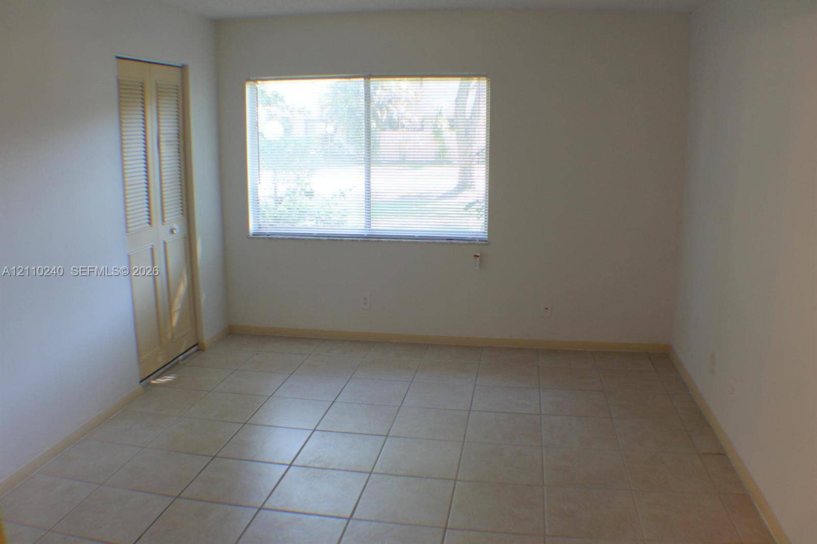 Interior space featuring large-format ceramic tile flooring, a horizontal sliding window, and a louvered bi-fold closet door