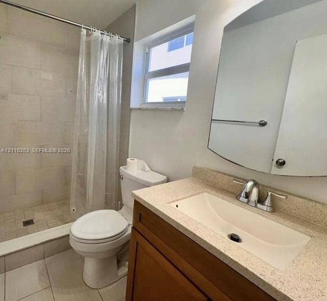 Bathroom featuring a vanity with a light-toned solid surface countertop and integrated basin, a stall shower with tiled walls, large-format floor tile, and a wall-mounted mirrored cabinet