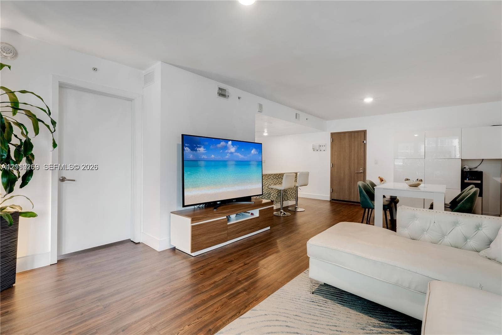 Open-concept interior featuring wood-finish flooring, recessed lighting, and a kitchen peninsula with a tiled front