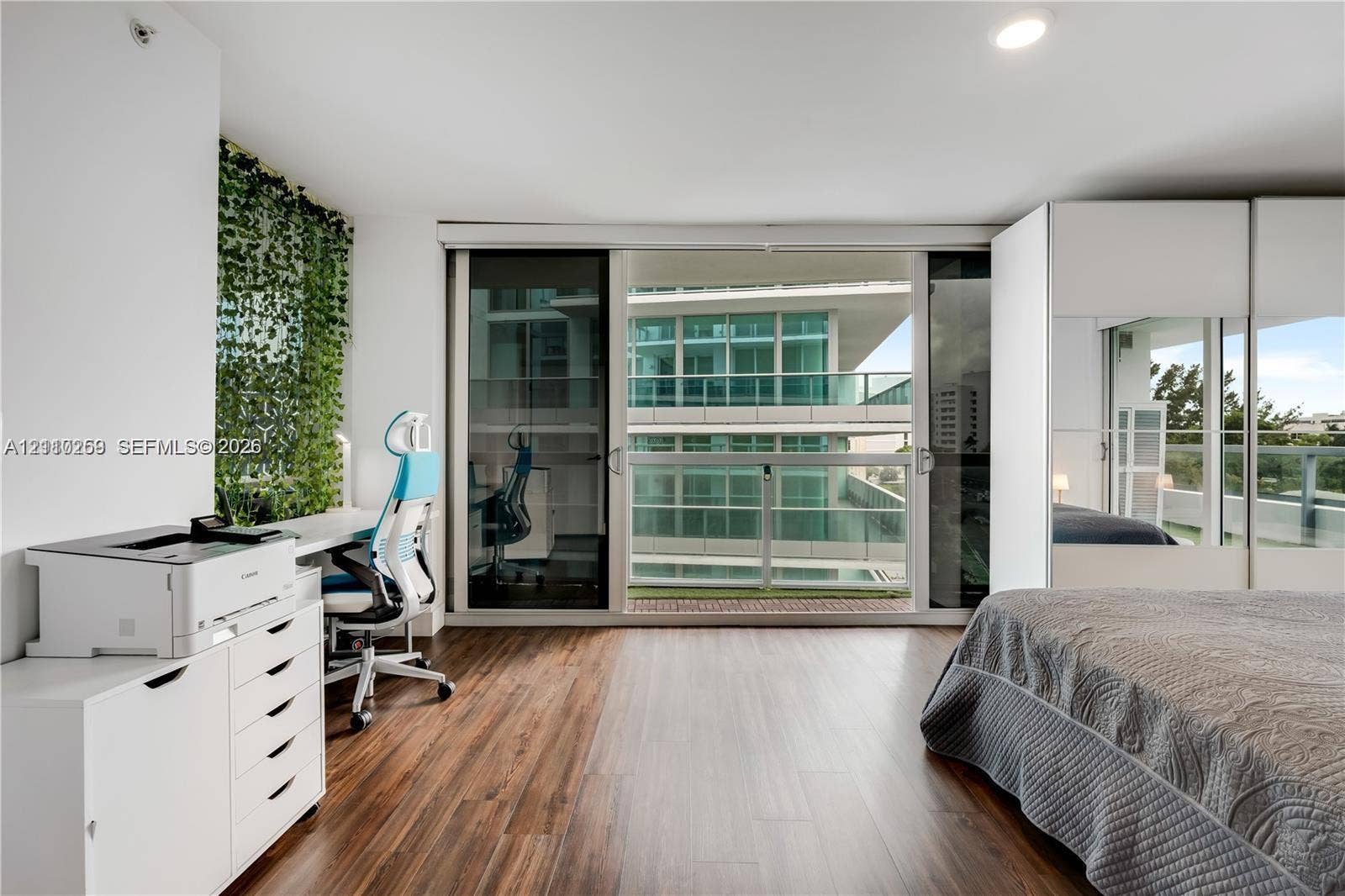 Wood-finish flooring, sliding glass balcony doors, built-in floor-to-ceiling cabinetry, recessed lighting, and integrated wall shelving