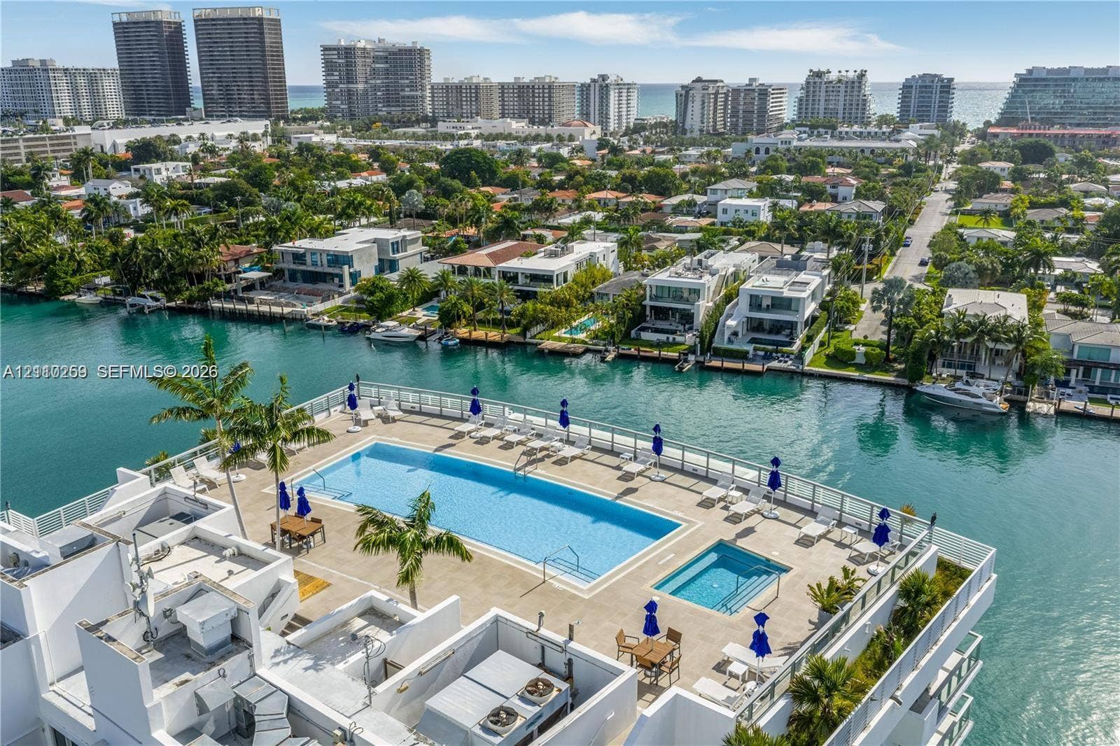 Rooftop terrace featuring a rectangular swimming pool, integrated spa, paved sun deck, and metal railings overlooking the waterway