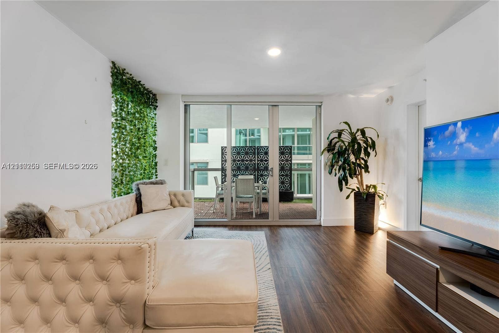Wood-finish flooring, full-height floor-to-ceiling sliding glass doors, recessed lighting, and a vertical living wall accent