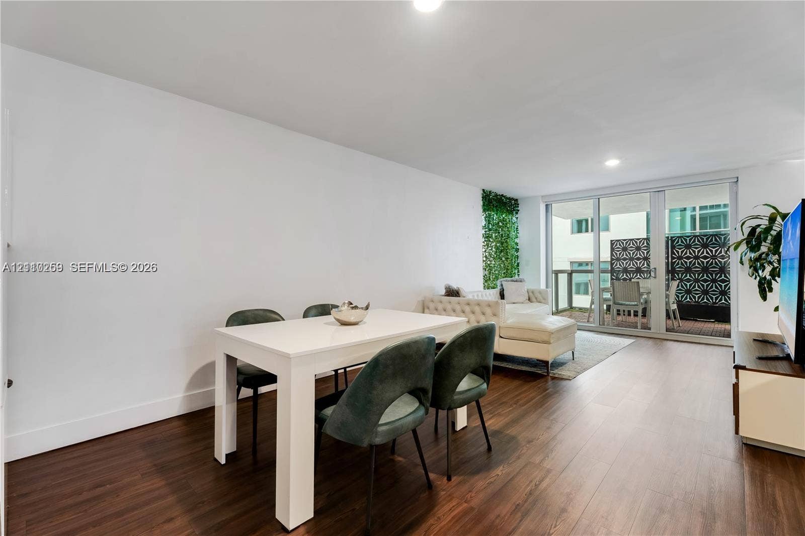 Living area featuring wood-finish flooring, recessed lighting, and expansive floor-to-ceiling glass sliding doors leading to a private balcony