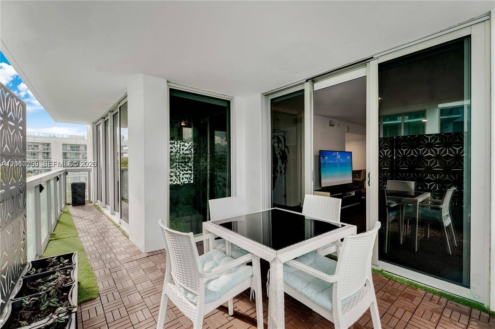 Covered balcony featuring tile flooring, decorative metal privacy screens, and multiple floor-to-ceiling glass sliding doors