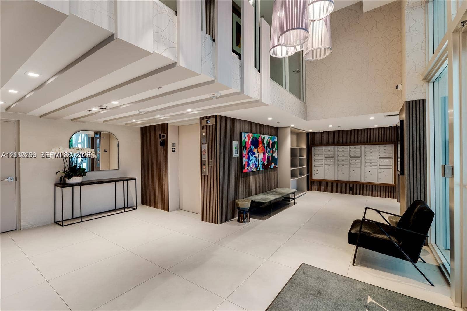 Lobby featuring large-format tile flooring, double-height ceilings, built-in elevator access, integrated mailboxes, and pendant lighting