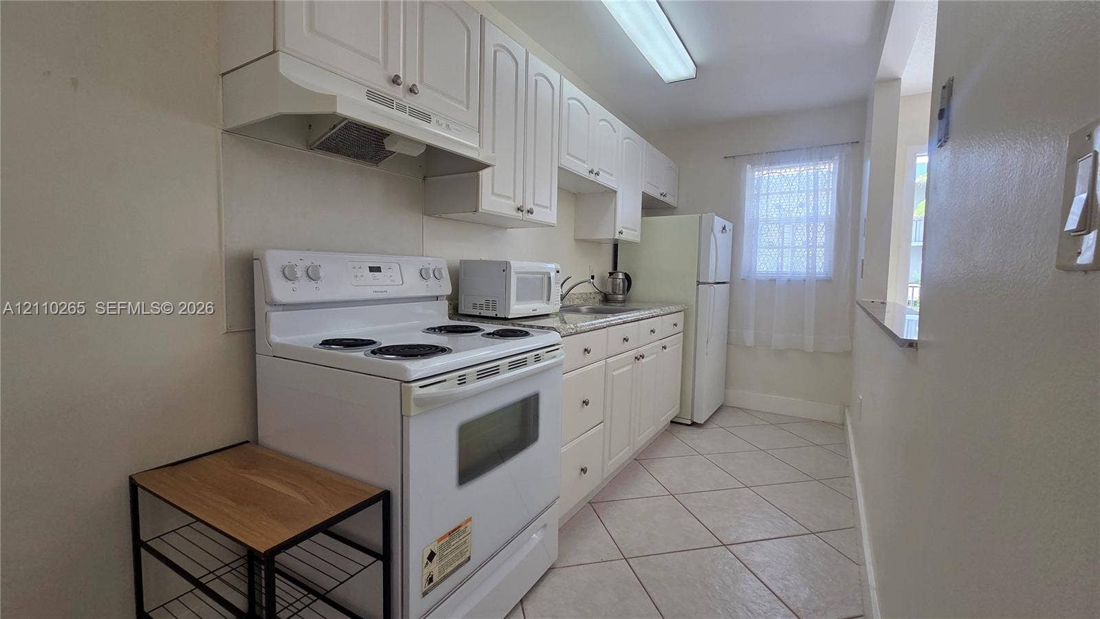 415 NE 2nd Street, #106, Hallandale Beach, Hallandale Beach, FL 33009 Kitchen featuring white cabinetry, stone-surface countertops, tile flooring, and integrated white appliances
