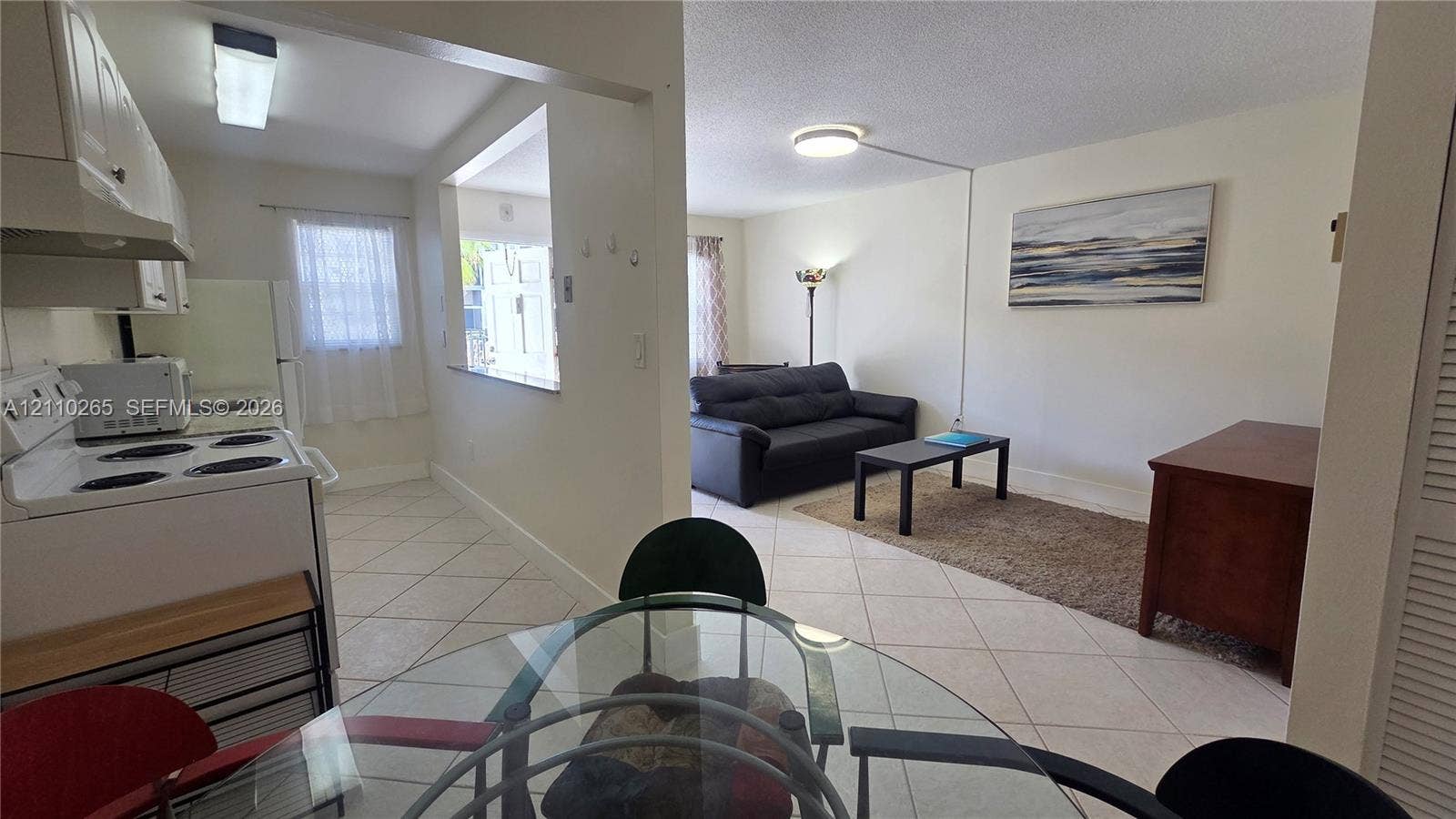 415 NE 2nd Street, #106, Hallandale Beach, Hallandale Beach, FL 33009 Ceramic tile flooring throughout, white cabinetry, and a kitchen pass-through window