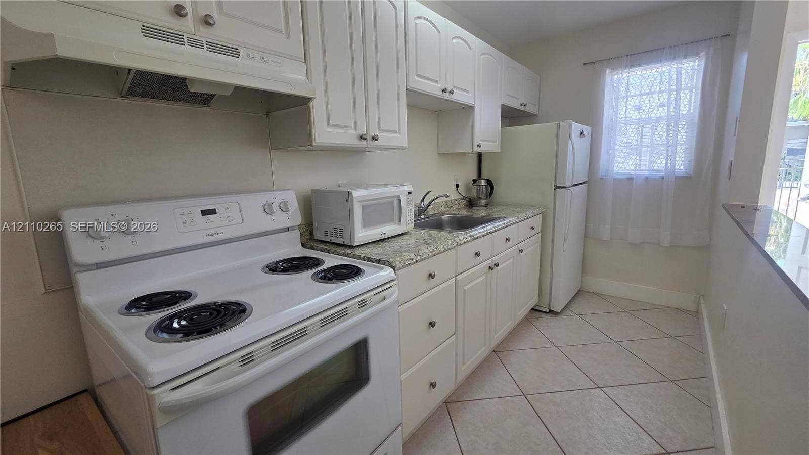 415 NE 2nd Street, #106, Hallandale Beach, Hallandale Beach, FL 33009 Kitchen featuring white cabinetry, stone-finish countertops, stainless steel sink, tile flooring, and integrated white appliances