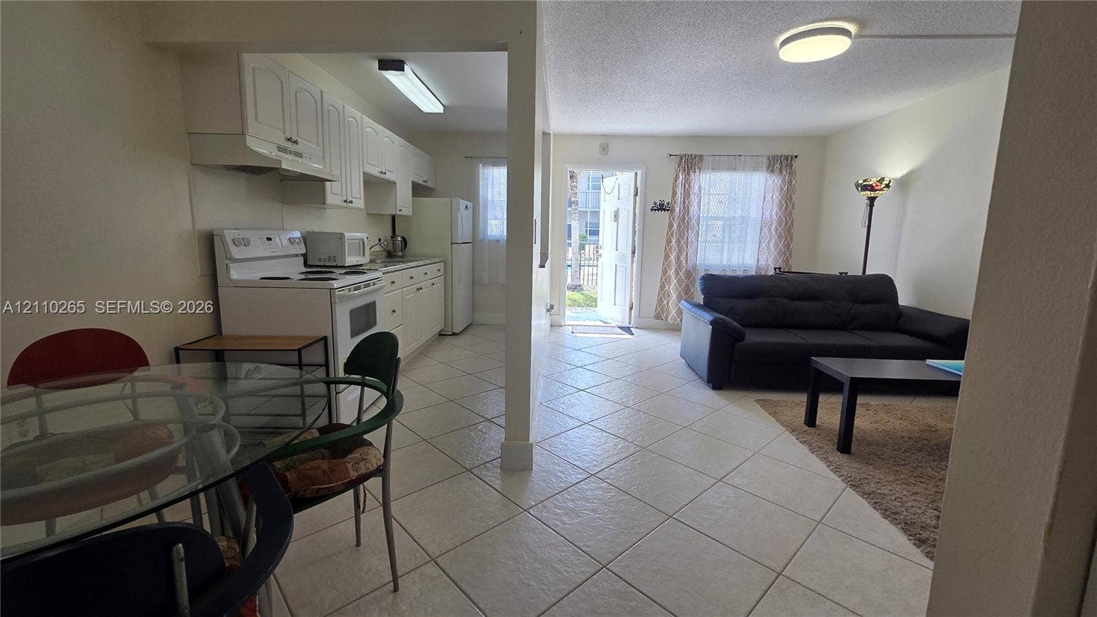 415 NE 2nd Street, #106, Hallandale Beach, Hallandale Beach, FL 33009 Kitchen area featuring white cabinetry, a slide-in range, and a neutral tile floor extending throughout the living space