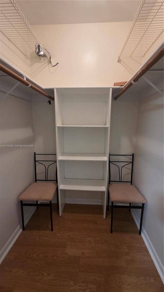 415 NE 2nd Street, #106, Hallandale Beach, Hallandale Beach, FL 33009 Walk-in closet featuring wood-finish flooring, built-in shelving unit, and dual-level wire hanging rods