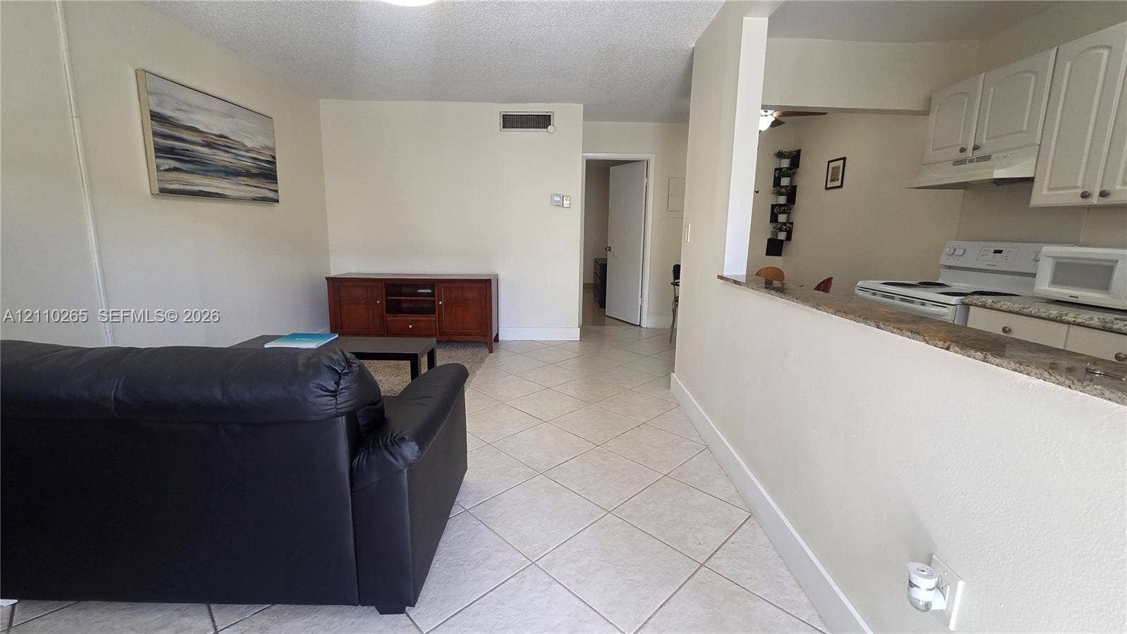 415 NE 2nd Street, #106, Hallandale Beach, Hallandale Beach, FL 33009 Interior featuring diagonal ceramic tile flooring, kitchen pass-through window with a stone-finish countertop, and white shaker-style cabinetry